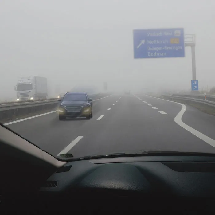 Blick aus dem Cockpit eines Fahrzeuges. Nebel und schlechte Sicht. Anderes Fahrzeug kommt auf der Autobahn als Geisterfahrer entgegen.